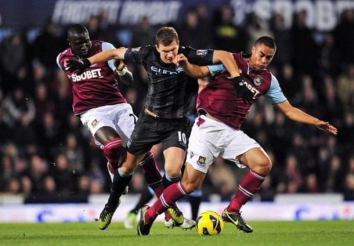 Manchester City's striker Edin Dzeko (C) clashes with West Ham's defender Winston Reid (R) and midfielder Mohamed Diame